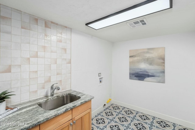 kitchen with sink, light tile patterned floors, backsplash, and dark stone counters