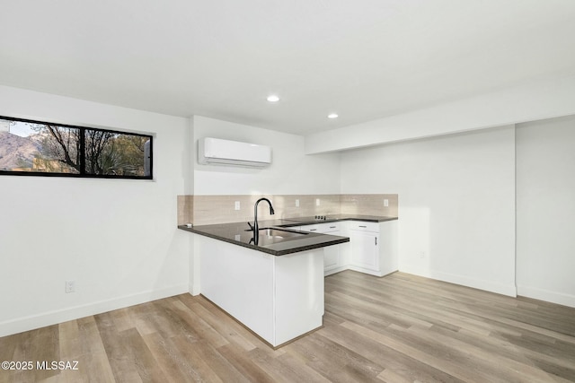 kitchen featuring tasteful backsplash, sink, a wall mounted AC, white cabinets, and kitchen peninsula