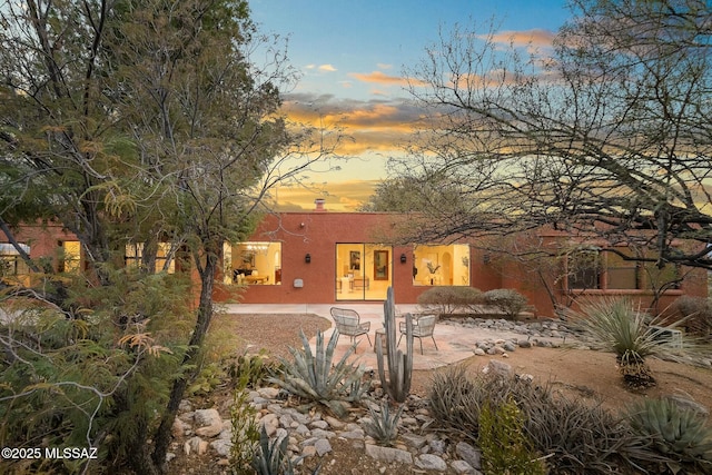 back house at dusk with a patio area