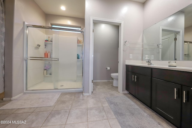 bathroom featuring tile patterned flooring, vanity, toilet, and a shower with door