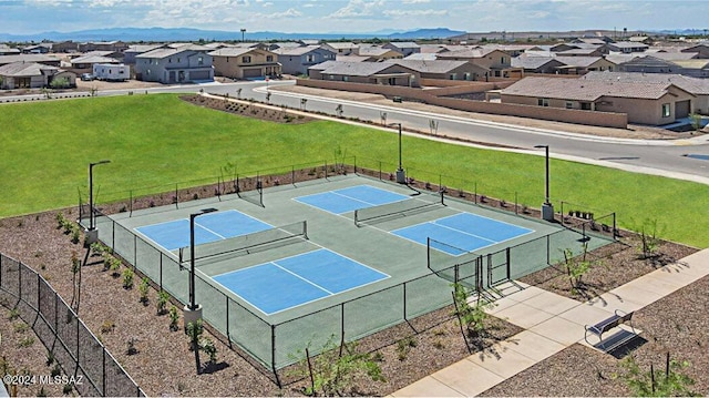 view of tennis court featuring a mountain view and a yard