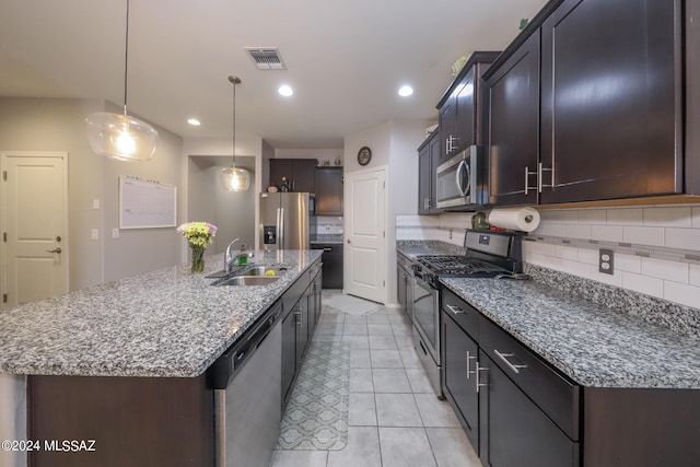 kitchen with a center island with sink, sink, decorative light fixtures, dark brown cabinets, and stainless steel appliances