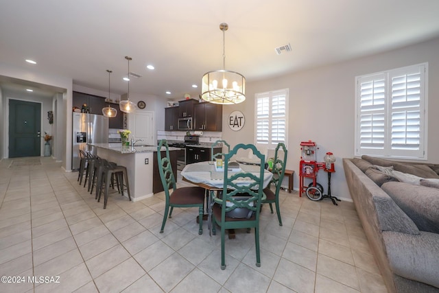 dining room with light tile patterned floors, sink, and an inviting chandelier