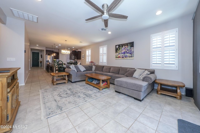 tiled living room with ceiling fan with notable chandelier