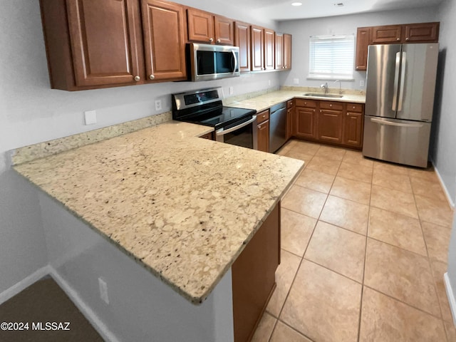 kitchen with sink, light tile patterned floors, appliances with stainless steel finishes, light stone counters, and kitchen peninsula