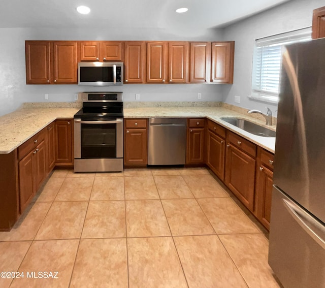 kitchen featuring kitchen peninsula, light stone countertops, stainless steel appliances, sink, and light tile patterned flooring