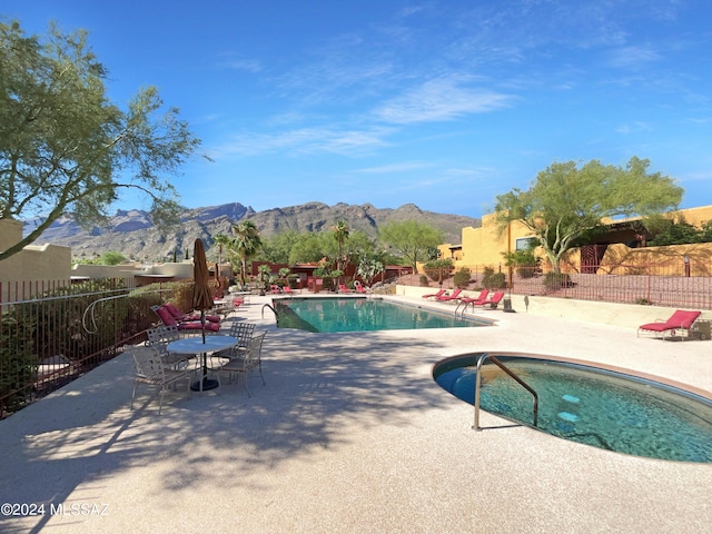 view of swimming pool featuring a mountain view, a patio, and a hot tub