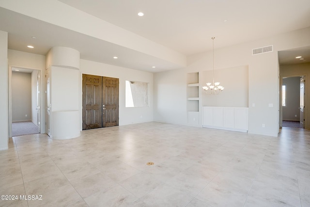 unfurnished room with a chandelier and built in features