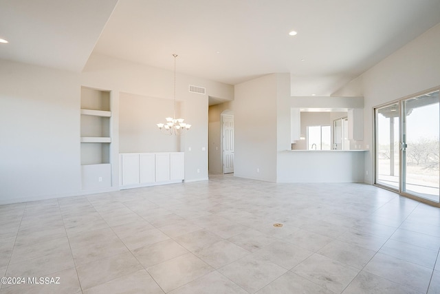 unfurnished living room featuring a chandelier and built in shelves