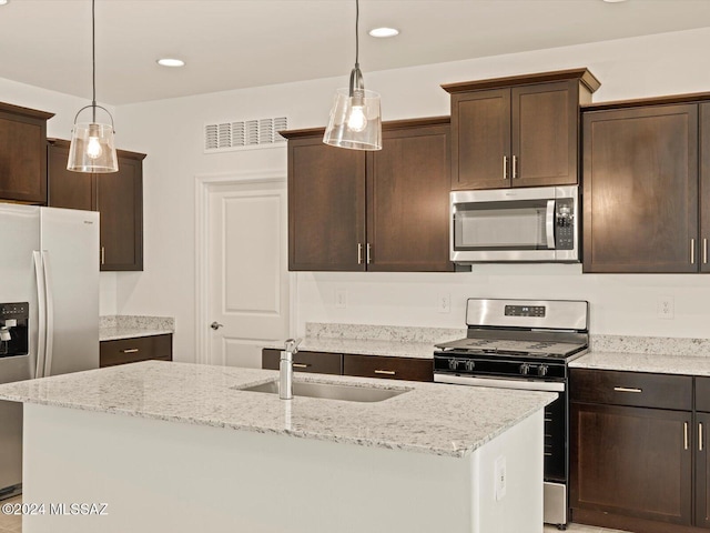 kitchen with stainless steel appliances, a kitchen island with sink, pendant lighting, and sink