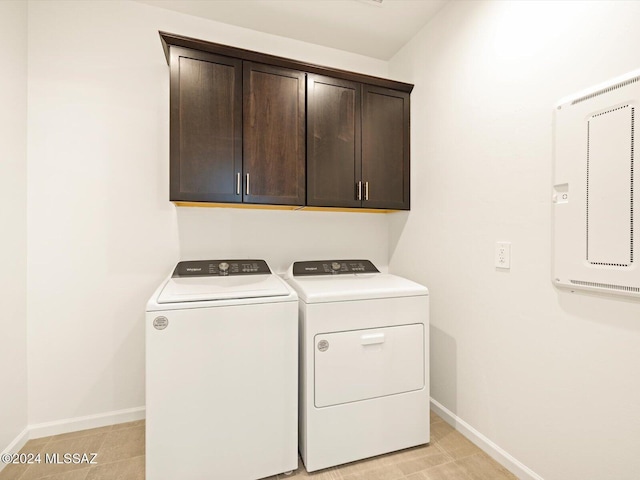 laundry area featuring washer and clothes dryer, light tile patterned flooring, and cabinets