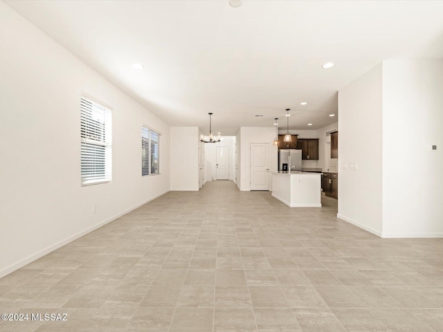 unfurnished living room featuring a notable chandelier