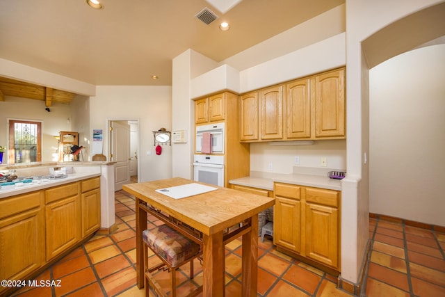 kitchen with beamed ceiling, light tile patterned flooring, and double oven