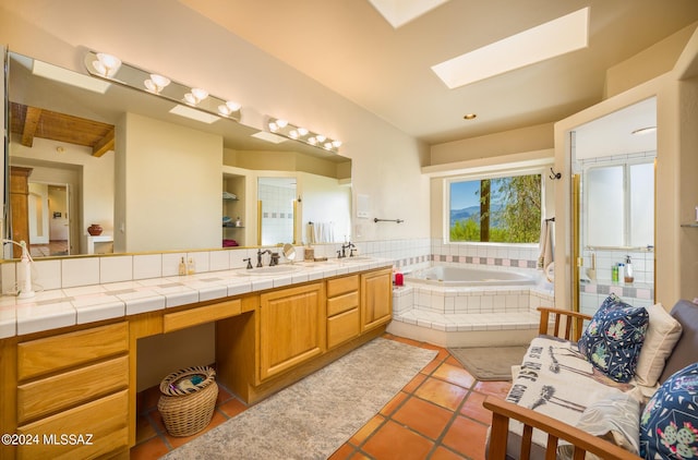 bathroom with tile patterned floors, vanity, tiled bath, and a skylight