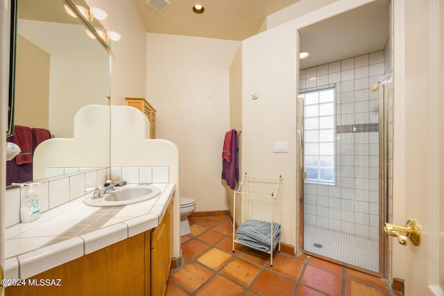 bathroom featuring tile patterned flooring, vanity, walk in shower, and toilet