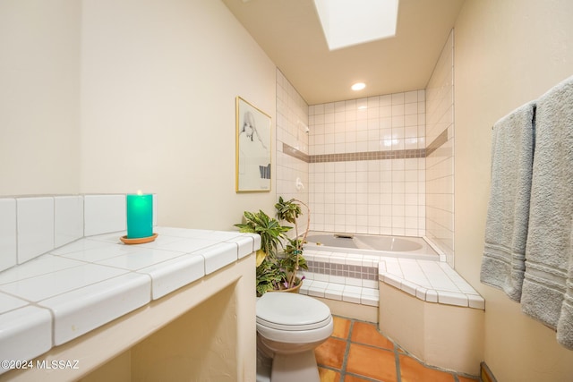 bathroom featuring tiled tub, toilet, tile patterned floors, and a skylight