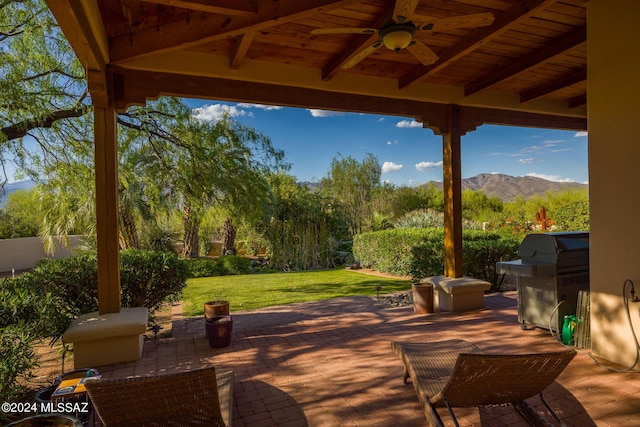 view of patio featuring ceiling fan, a grill, and a mountain view