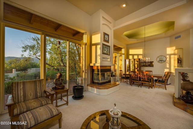 carpeted living room featuring a notable chandelier, a tray ceiling, and a fireplace