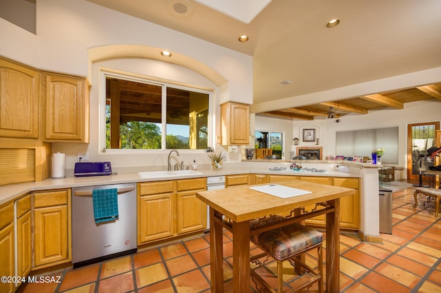 kitchen with sink, stainless steel dishwasher, kitchen peninsula, light brown cabinets, and beam ceiling