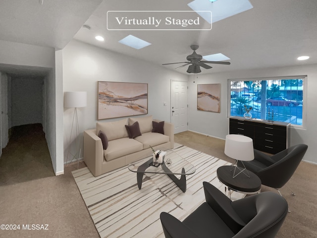 carpeted living room featuring lofted ceiling with skylight and ceiling fan