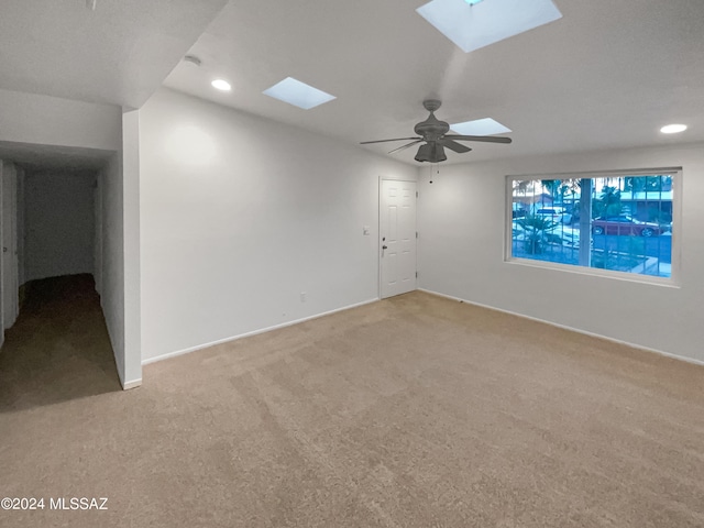 carpeted empty room featuring a skylight and ceiling fan