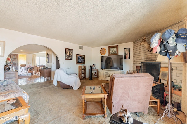 living room featuring light colored carpet, a textured ceiling, and a brick fireplace