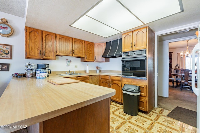 kitchen featuring kitchen peninsula, sink, a chandelier, oven, and range hood