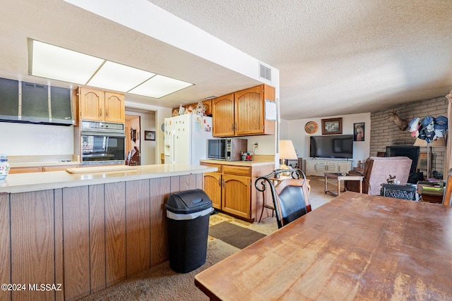 kitchen with kitchen peninsula, light carpet, white fridge with ice dispenser, and a textured ceiling