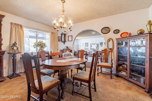 carpeted dining area featuring a textured ceiling and a notable chandelier