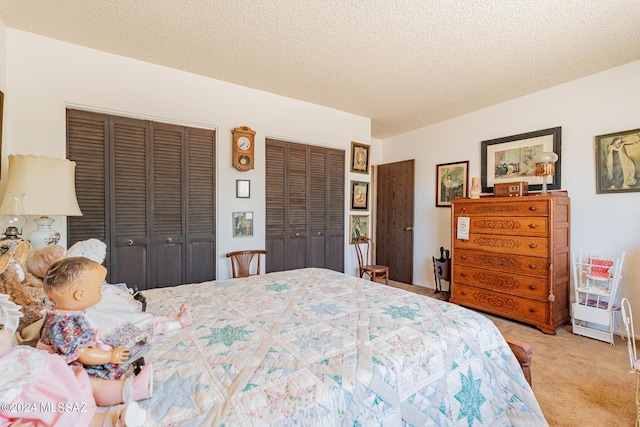 carpeted bedroom featuring two closets and a textured ceiling