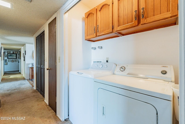 laundry area featuring cabinets, light colored carpet, a textured ceiling, and washing machine and clothes dryer