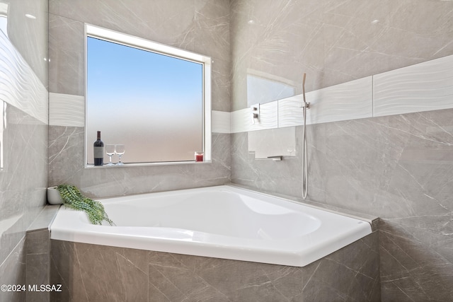 bathroom featuring tiled bath and tile walls