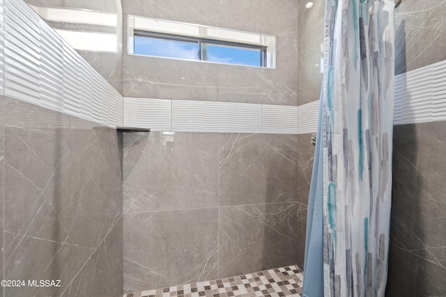 bathroom with tiled shower and a healthy amount of sunlight