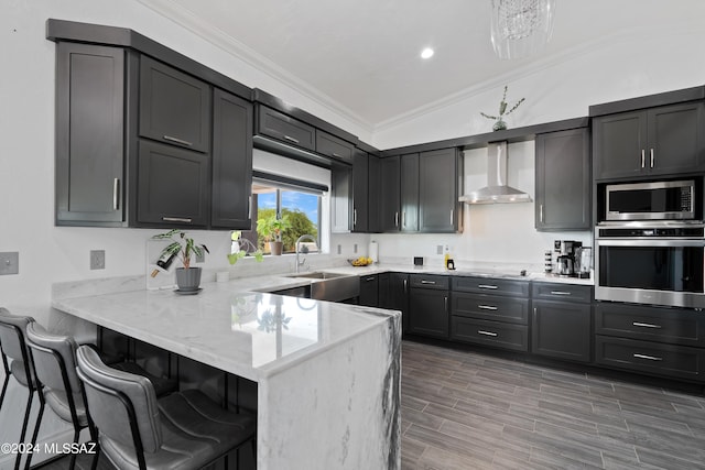 kitchen featuring stainless steel appliances, vaulted ceiling, wall chimney range hood, sink, and kitchen peninsula