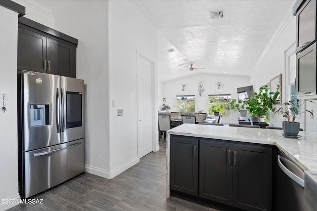 kitchen with kitchen peninsula, dark hardwood / wood-style floors, light stone countertops, appliances with stainless steel finishes, and vaulted ceiling