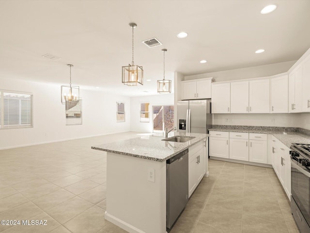 kitchen with decorative light fixtures, white cabinets, appliances with stainless steel finishes, and a kitchen island with sink