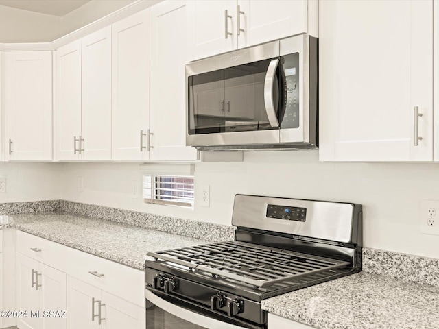 kitchen with appliances with stainless steel finishes, white cabinetry, and light stone countertops