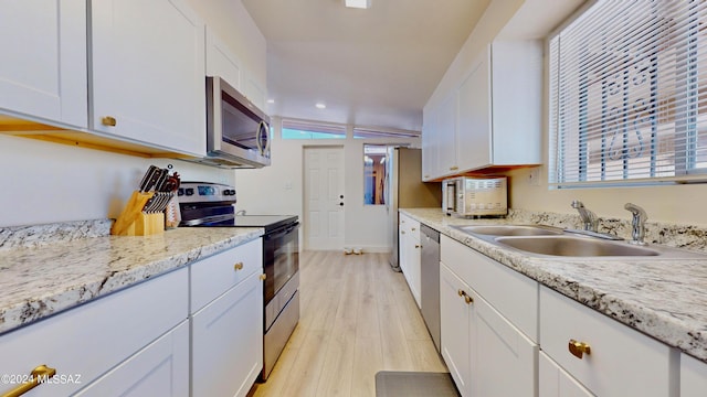 kitchen featuring stainless steel appliances, white cabinetry, lofted ceiling, and sink