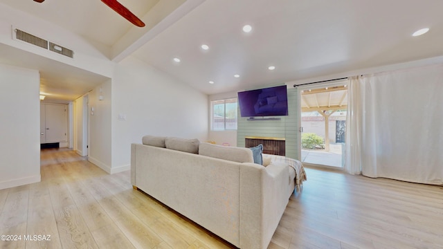 living room with a large fireplace, vaulted ceiling with beams, ceiling fan, and light hardwood / wood-style flooring