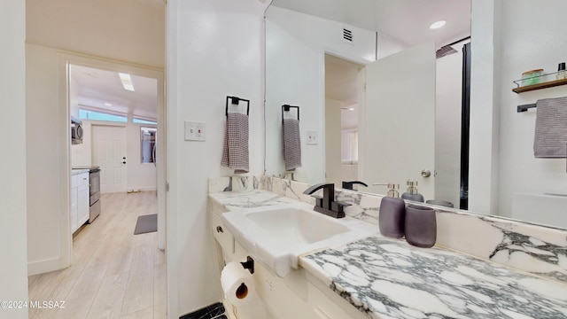 bathroom featuring hardwood / wood-style flooring, vanity, and vaulted ceiling