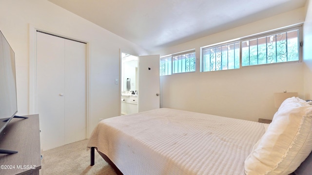 bedroom featuring ensuite bath, light carpet, and a closet