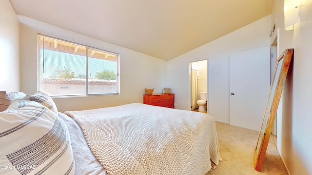 bedroom featuring ensuite bathroom, light carpet, and vaulted ceiling