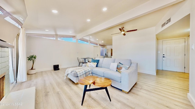 living room with lofted ceiling with beams, ceiling fan, a fireplace, and light hardwood / wood-style flooring