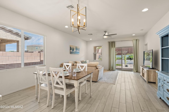 dining room with ceiling fan with notable chandelier, a wealth of natural light, and light hardwood / wood-style floors