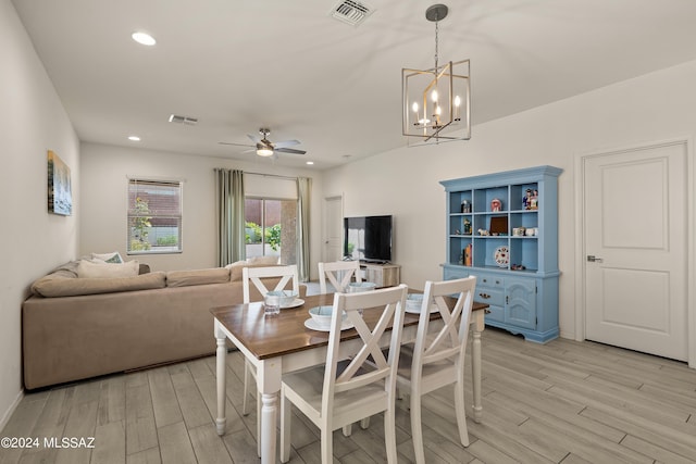 dining space featuring ceiling fan with notable chandelier and light hardwood / wood-style floors