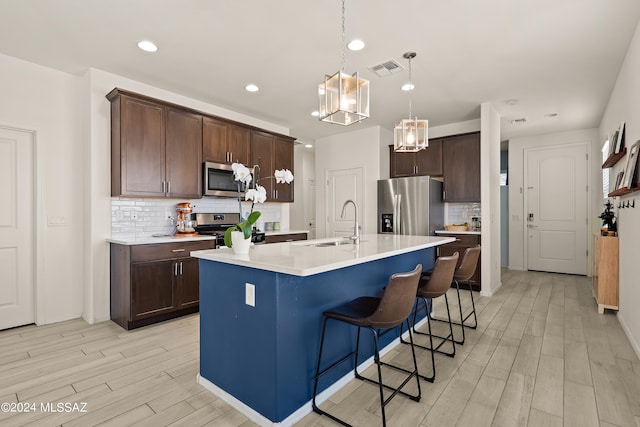 kitchen featuring appliances with stainless steel finishes, a center island with sink, dark brown cabinetry, and sink