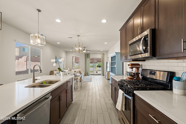 kitchen featuring ceiling fan, light hardwood / wood-style floors, pendant lighting, sink, and stainless steel appliances