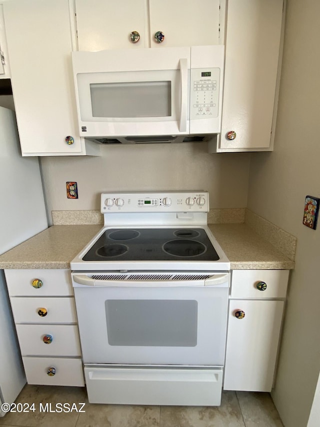 kitchen with white appliances, white cabinets, and light tile patterned flooring