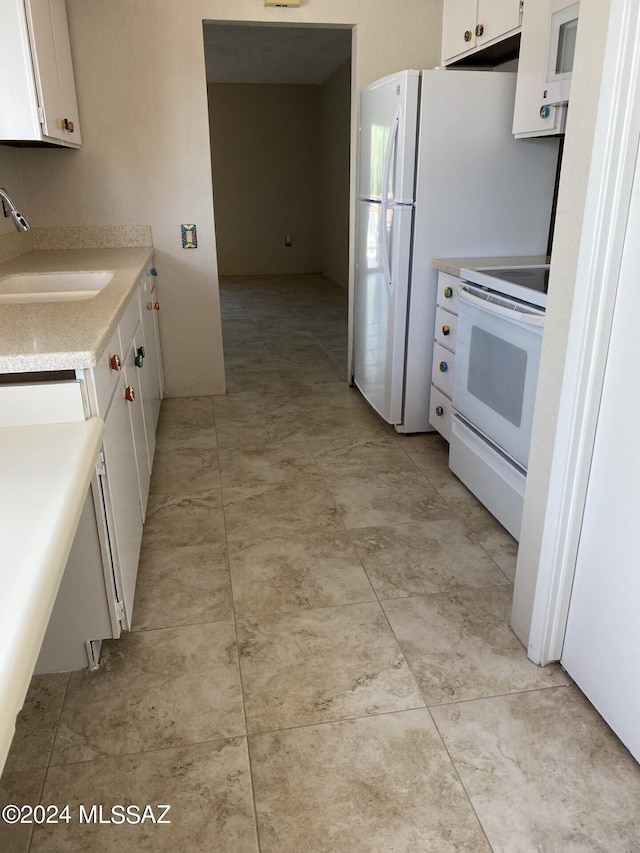 kitchen featuring sink, white appliances, and white cabinetry