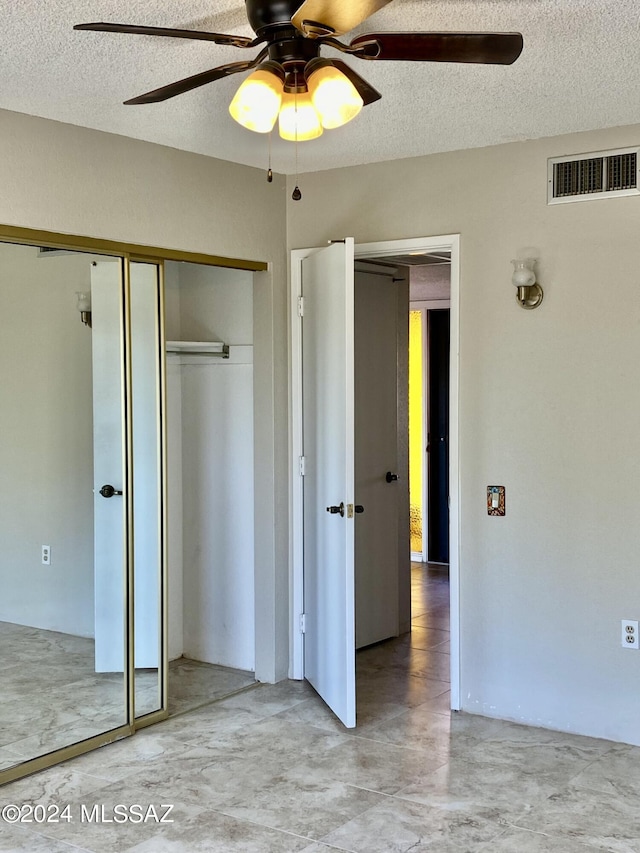 unfurnished bedroom with ceiling fan, a closet, and a textured ceiling